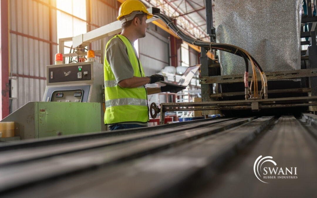 A factory worker operates a rubber processing machine inside industrial plant.